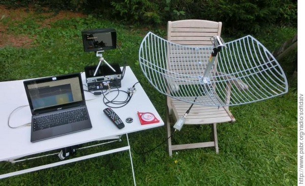 Image montrant un essai de réception DATV de l'ISS. La parabole est posée sur une chaise de jardin.